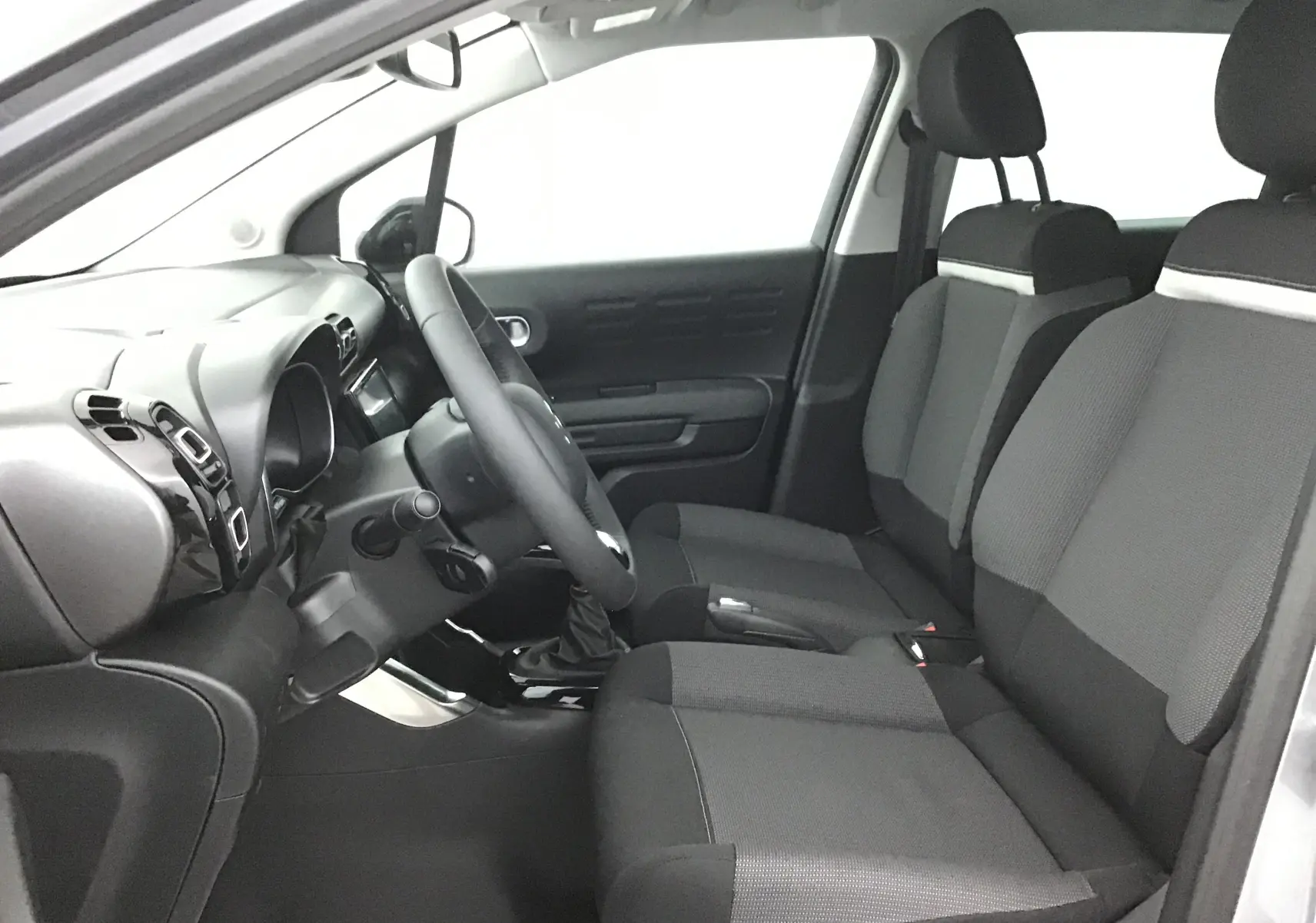 Vue intérieure côté conducteur de la Citroën C3 Aircross 2024 avec sièges gris et tableau de bord noir.