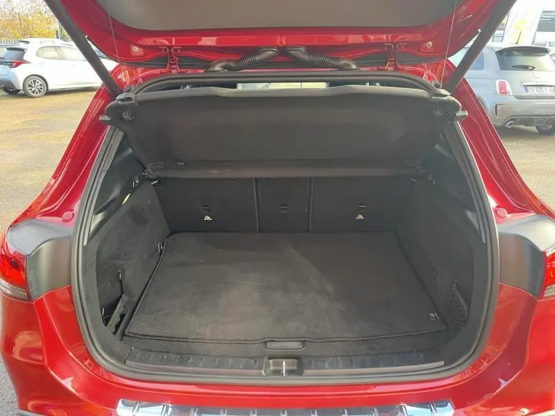 Coffre ouvert vu de l'arrière d'une Mercedes GLA 200 Business Line rouge Patagonie métallisé designo, intérieur noir.