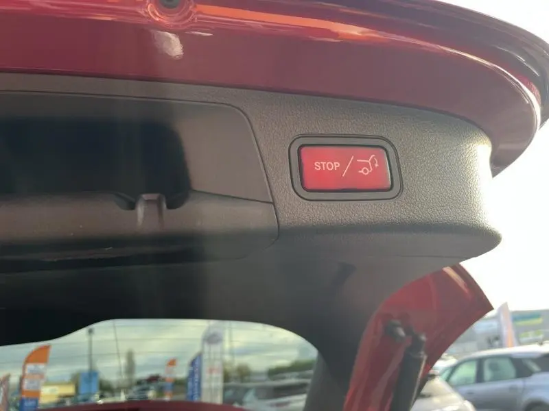 Détail du bouton stop d'ouverture électrique du coffre sur la partie intérieure rouge Patagonie métallisé du Mercedes GLA 200 Business Line.