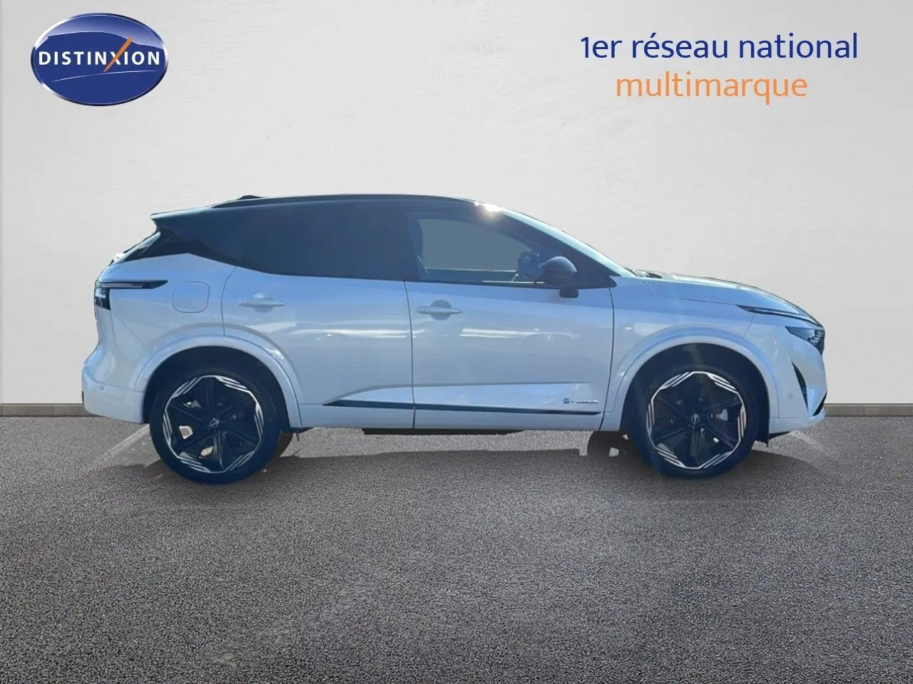 Profil droit du Nissan Qashqai 2025 blanc nacré avec toit noir et jantes noires distinctives en ville.