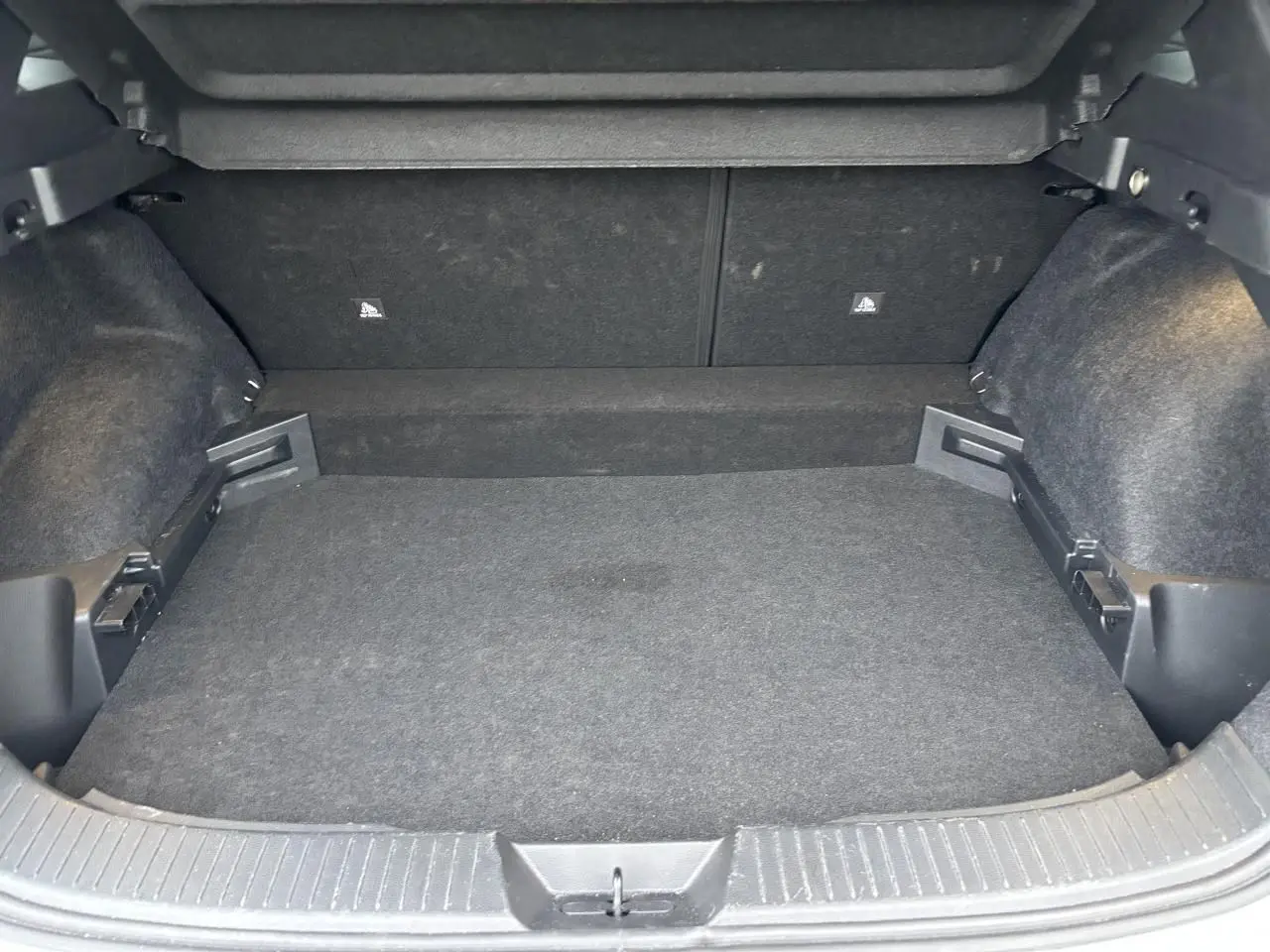 Coffre vide vu de l'arrière d'un Nissan Qashqai blanc nacré, montrant la moquette et les fixations ISOFIX.
