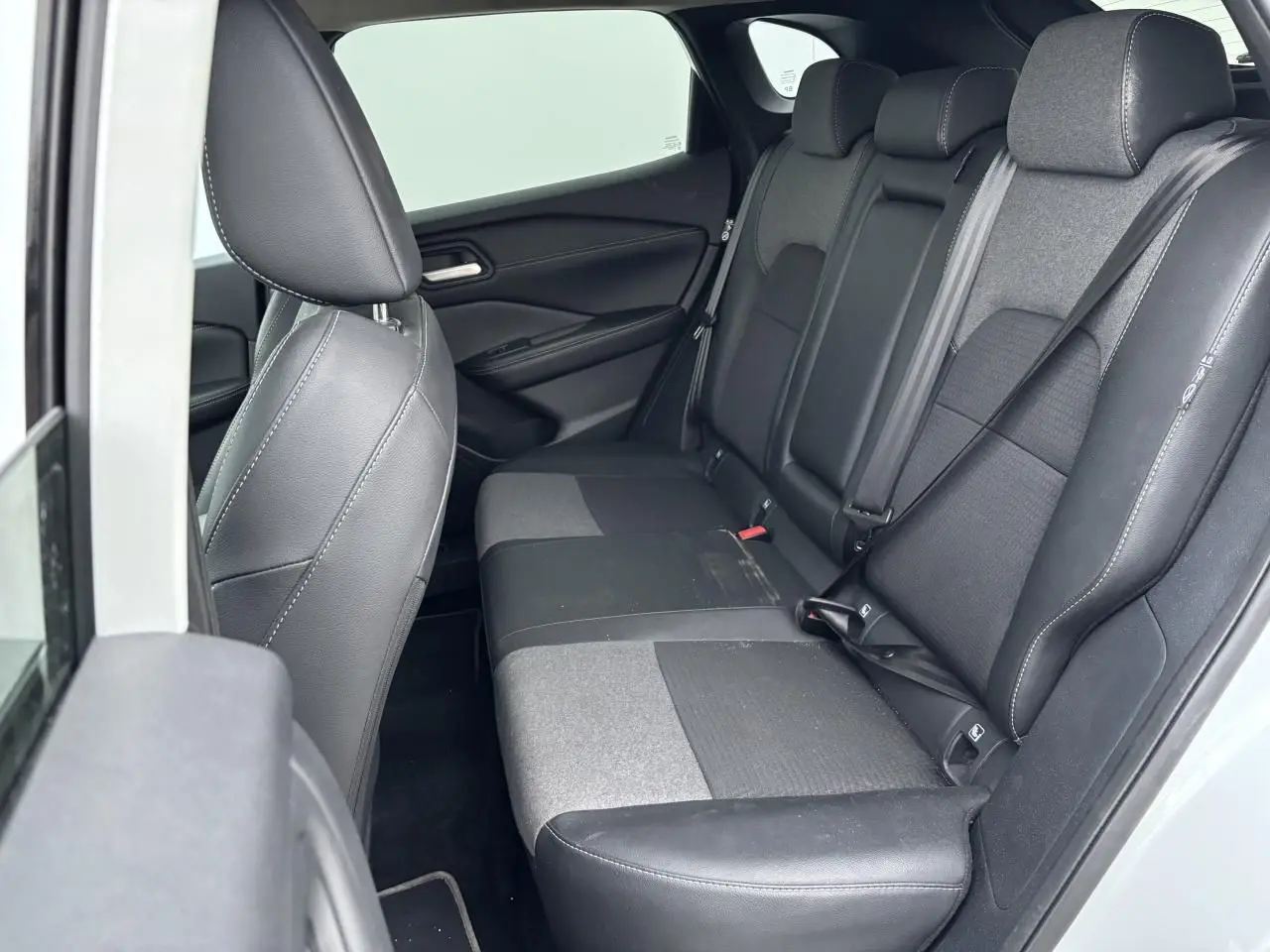 Vue intérieure côté gauche sur la banquette arrière mixte cuir et tissu noir du Nissan Qashqai blanc nacré 2025.
