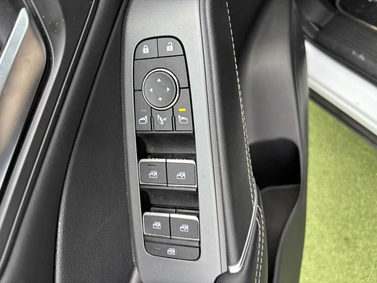 Gros plan sur les commandes de lève-vitres et rétroviseurs côté gauche intérieur du Nissan Qashqai blanc nacré 2025.