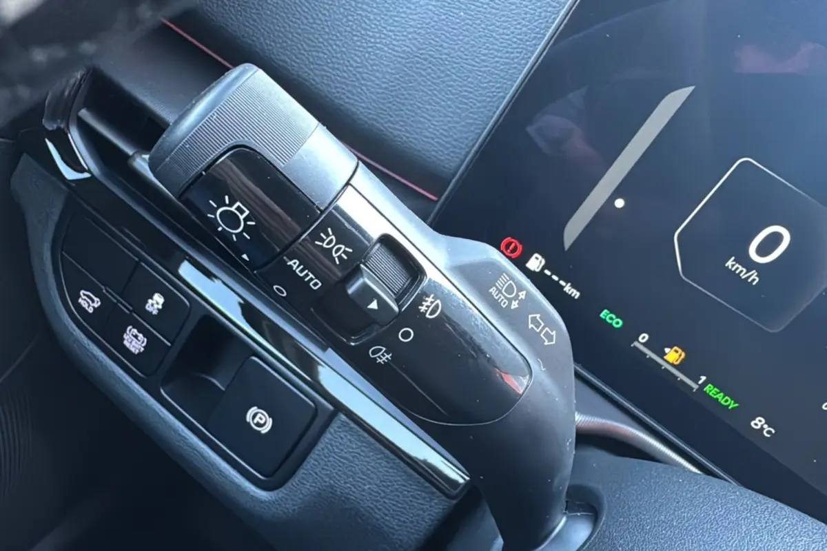 Gros plan sur la commande d’éclairage et tableau de bord numérique du Kia Sportage noir étoilé, affichant 0 km/h et mode ECO.