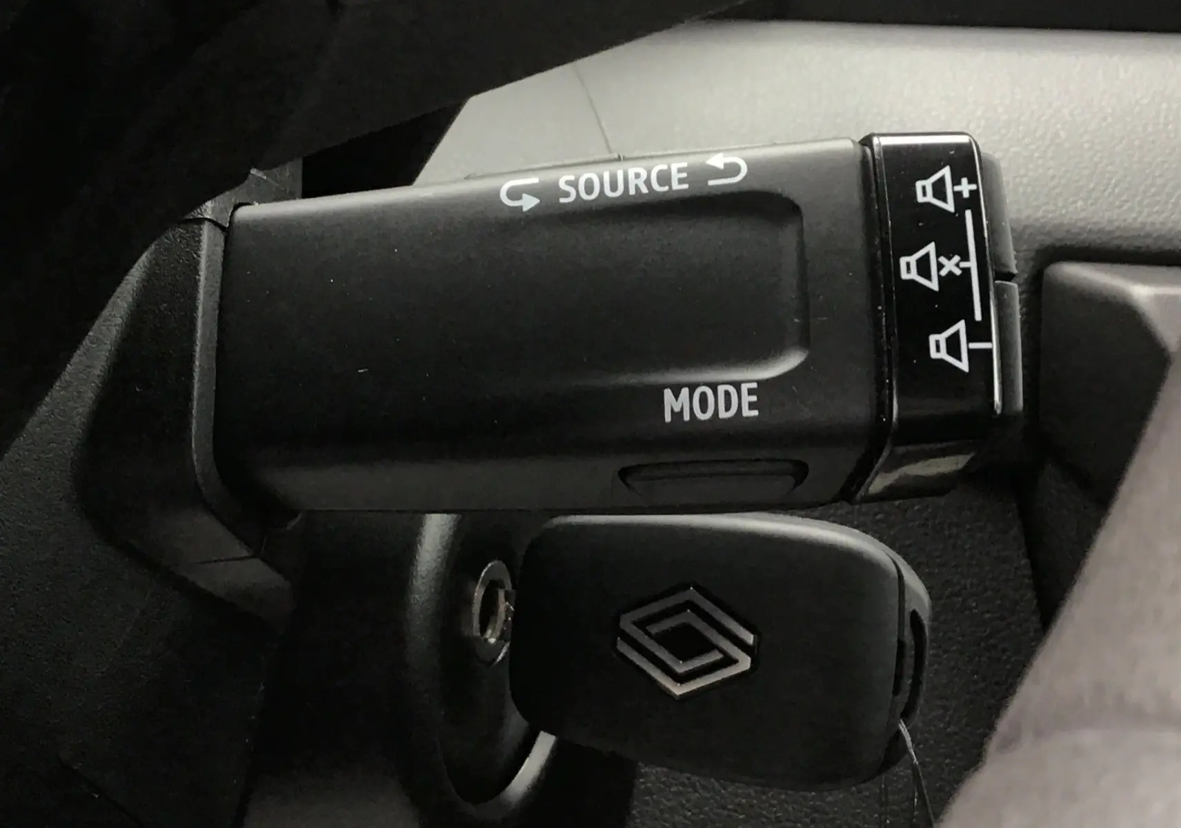 Gros plan sur la commande multimédia au volant du Renault Master 2025, avec clé insérée et boutons source et mode visibles.