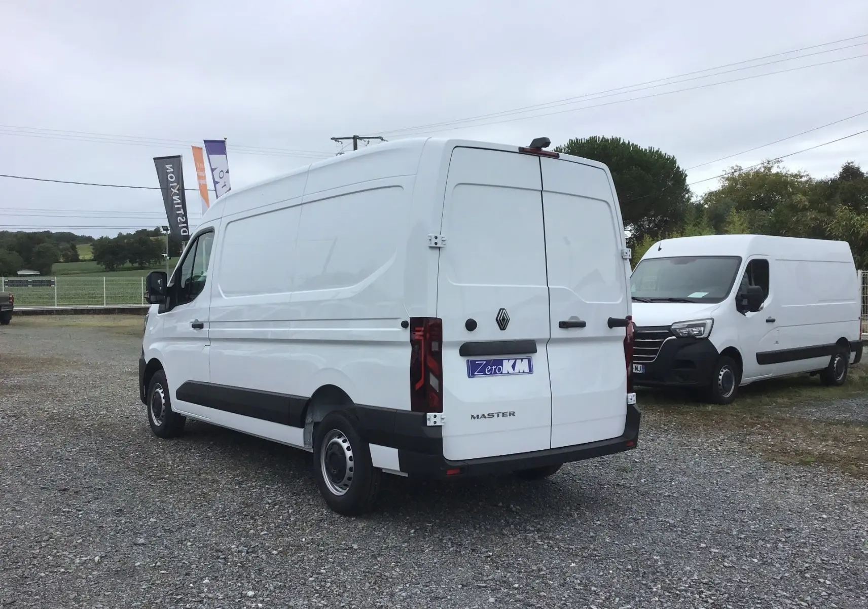 Vue 3/4 arrière gauche d’un Renault Master blanc 2025, fourgon utilitaire avec porte arrière double et bandeau noir latéral.