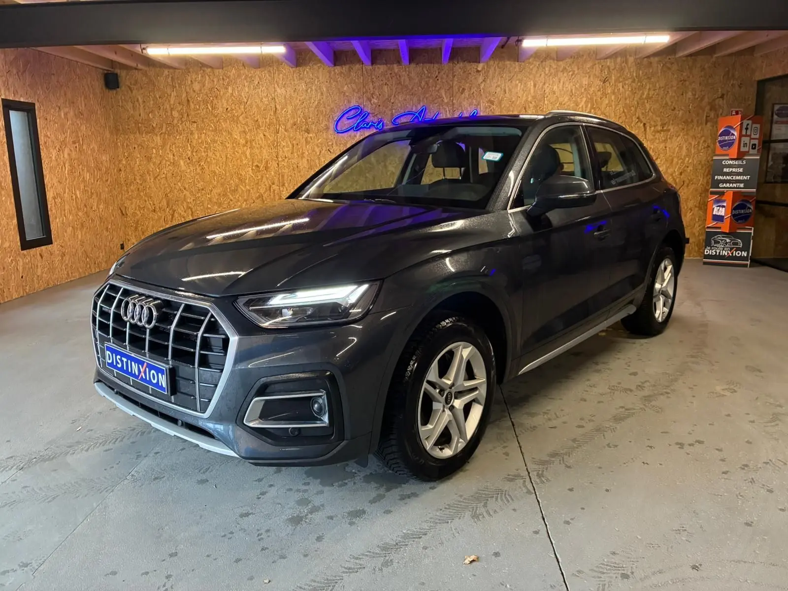 Audi Q5 gris en 3/4 avant droit, avec calandre large et jantes en alliage à 5 branches doubles.