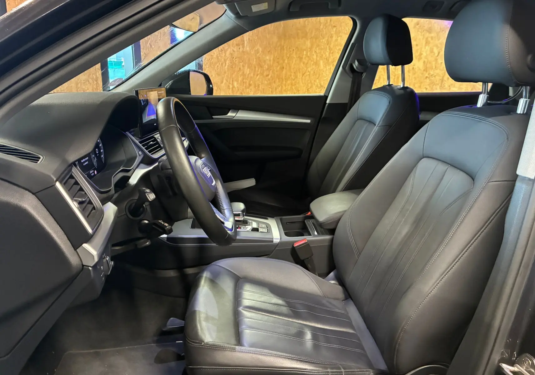 Vue intérieure côté conducteur de l'Audi Q5 2024, sièges en cuir noir et tableau de bord moderne.