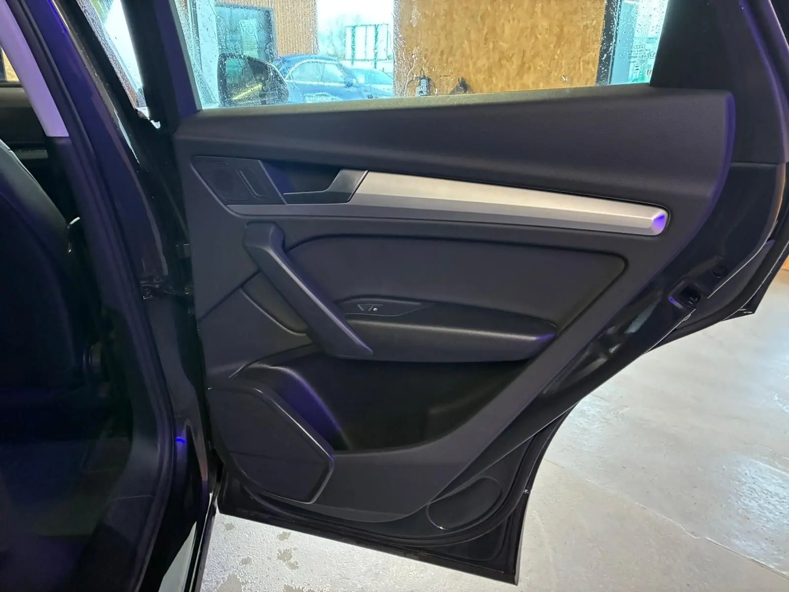 Vue intérieure de la porte arrière droite noire de l'Audi Q5 2024 avec insert argenté et haut-parleur intégré.