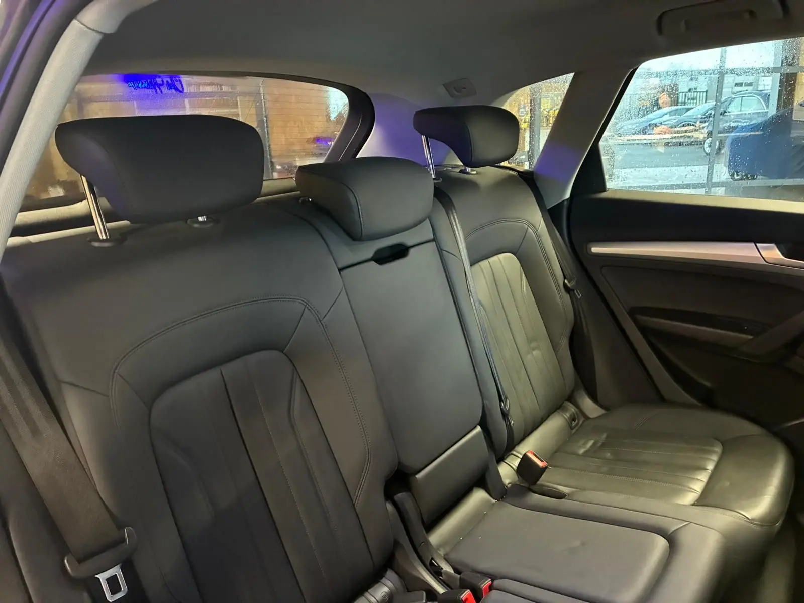 Vue intérieure sur la banquette arrière en cuir noir de l'Audi Q5 2024, avec appuie-têtes et ceintures visibles.