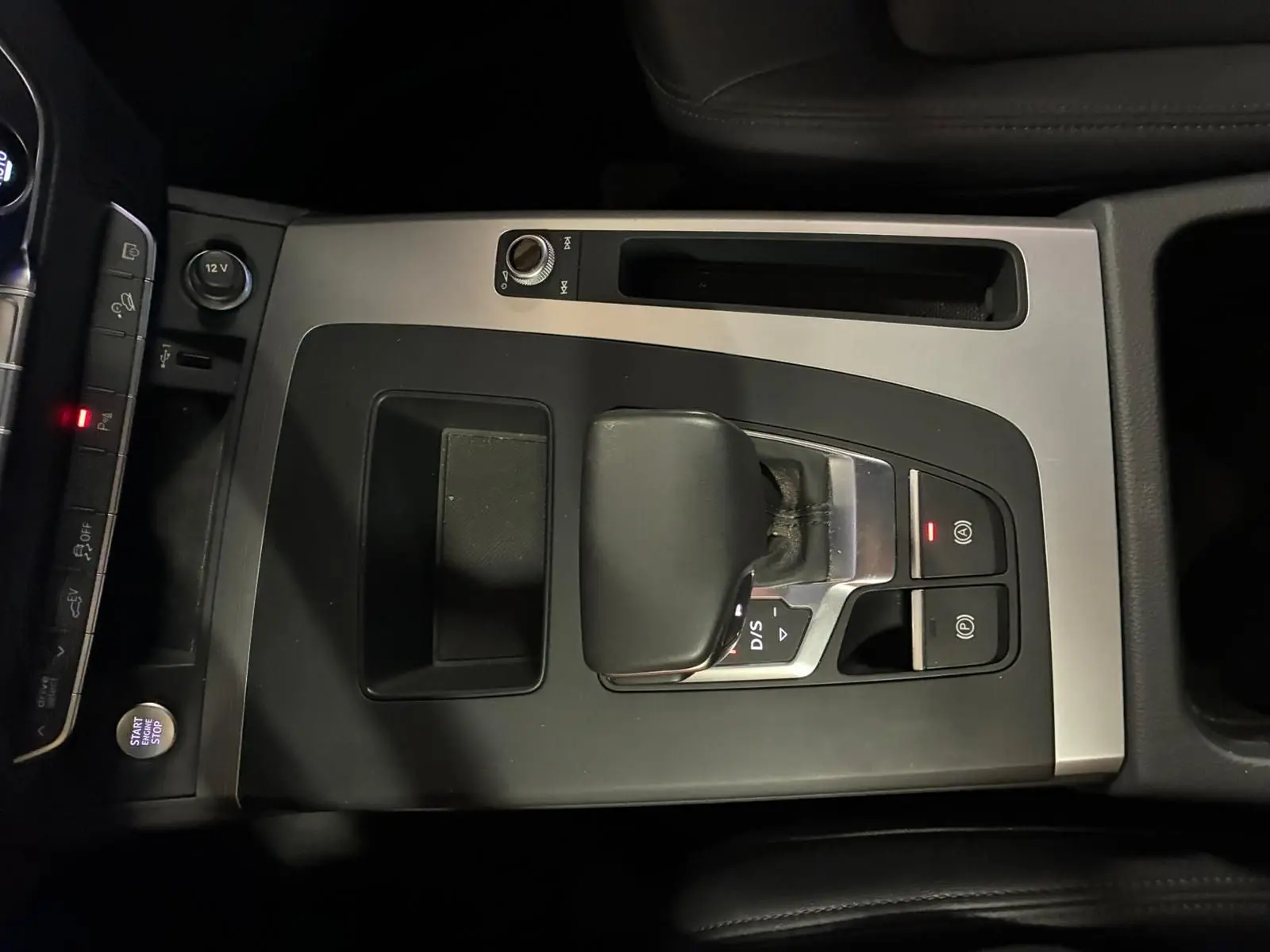 Vue rapprochée de la console centrale grise et noire de l’Audi Q5 2024 avec levier de vitesse S tronic et bouton Start/Stop.