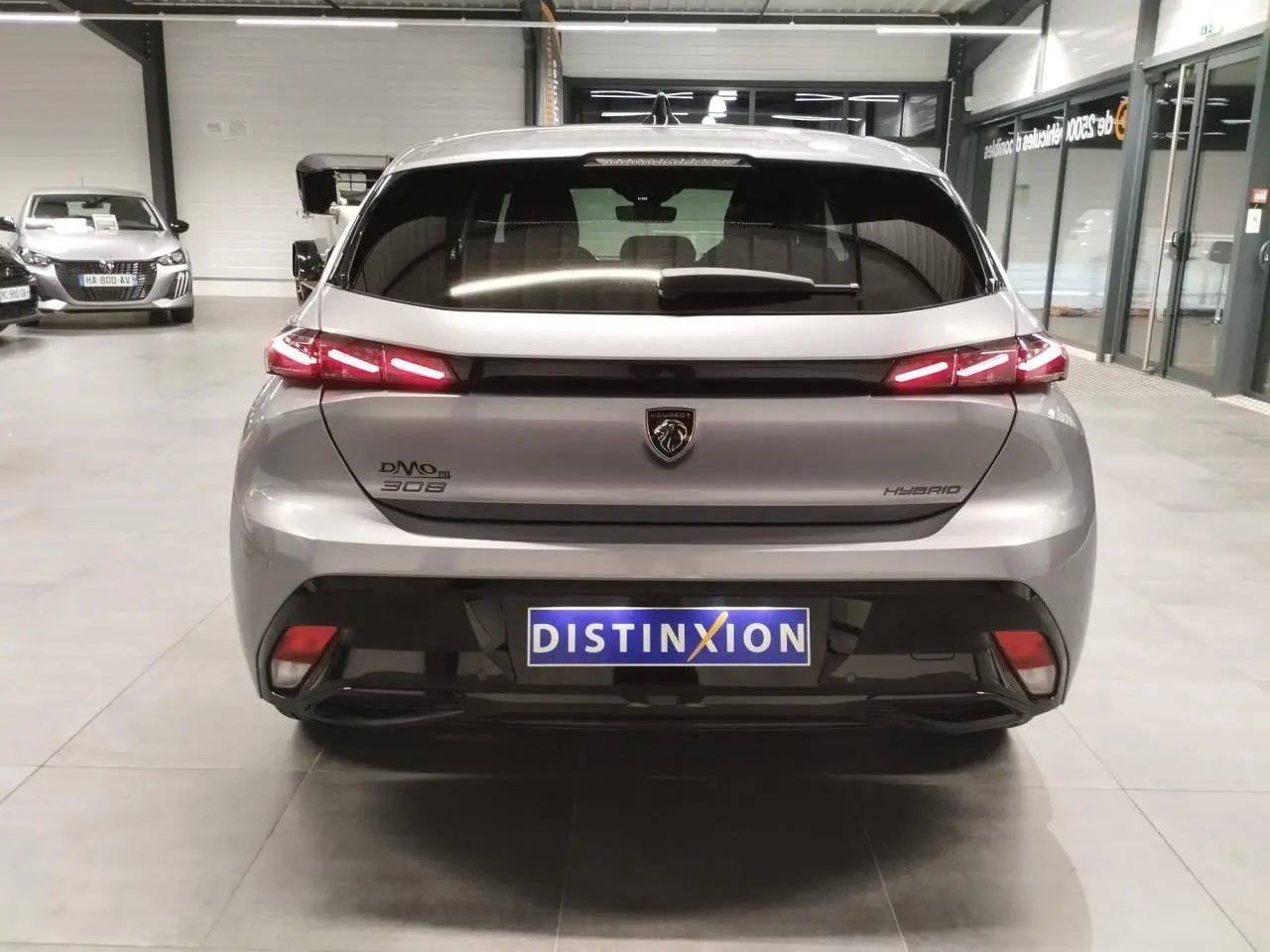 Vue arrière d'une Peugeot 308 gris Artense avec feux arrière LED en forme de griffes et logo lion central.