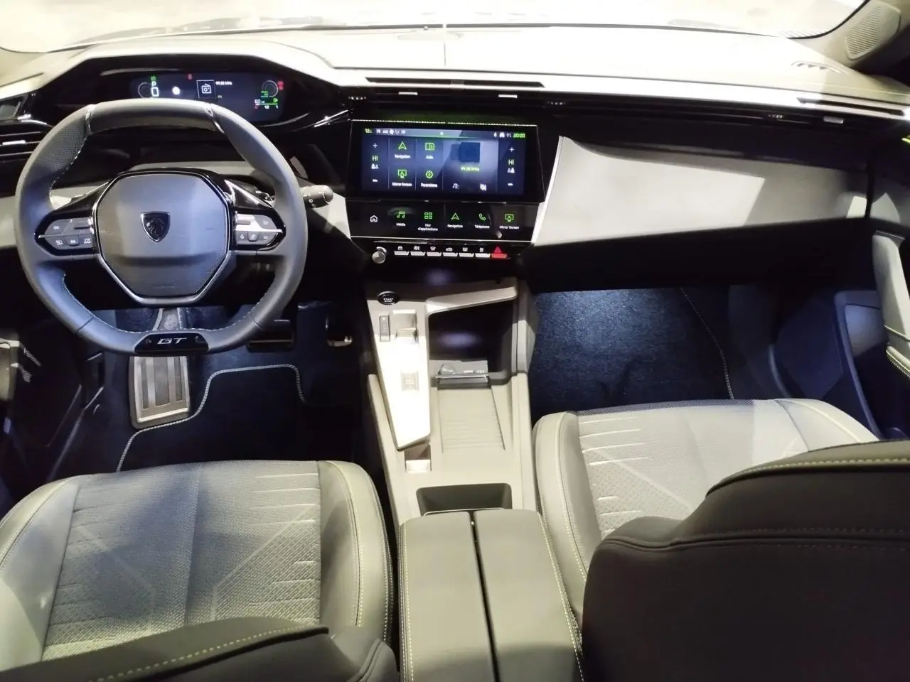 Vue intérieure avant de la Peugeot 308 GT 2026, tableau de bord noir avec écran tactile et volant compact GT cuir.