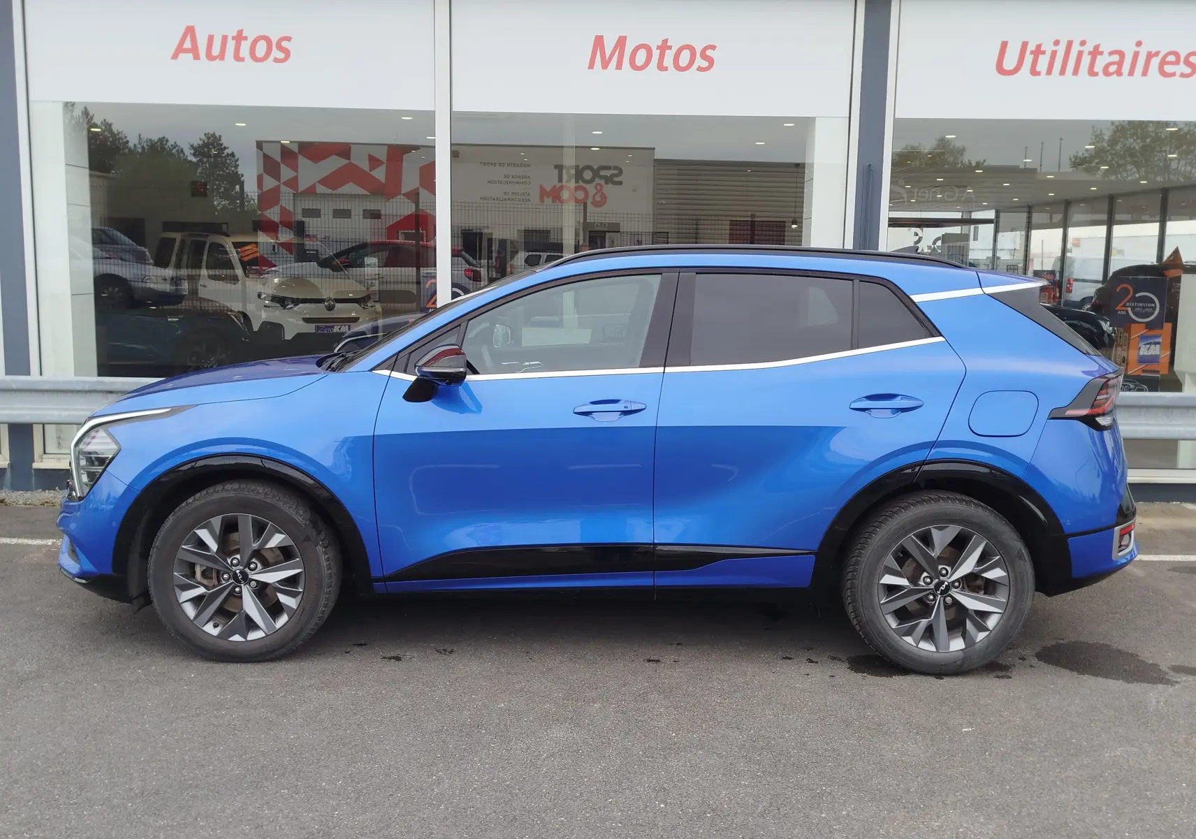 Vue de profil côté gauche d'un KIA SPORTAGE bleu fusion métallisé, soulignant ses lignes modernes et ses jantes alliage.