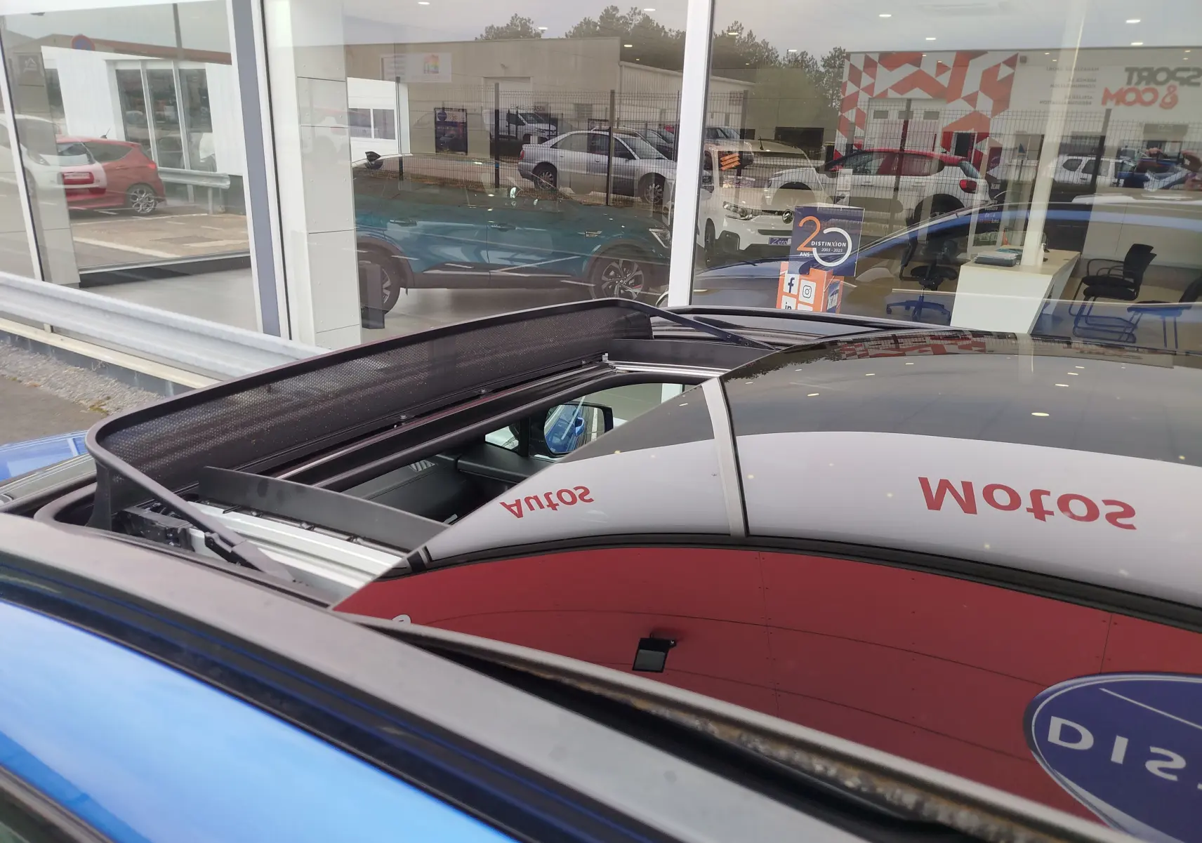 Vue rapprochée du toit ouvrant panoramique du Kia Sportage bleu fusion métallisé, avec reflet du showroom.