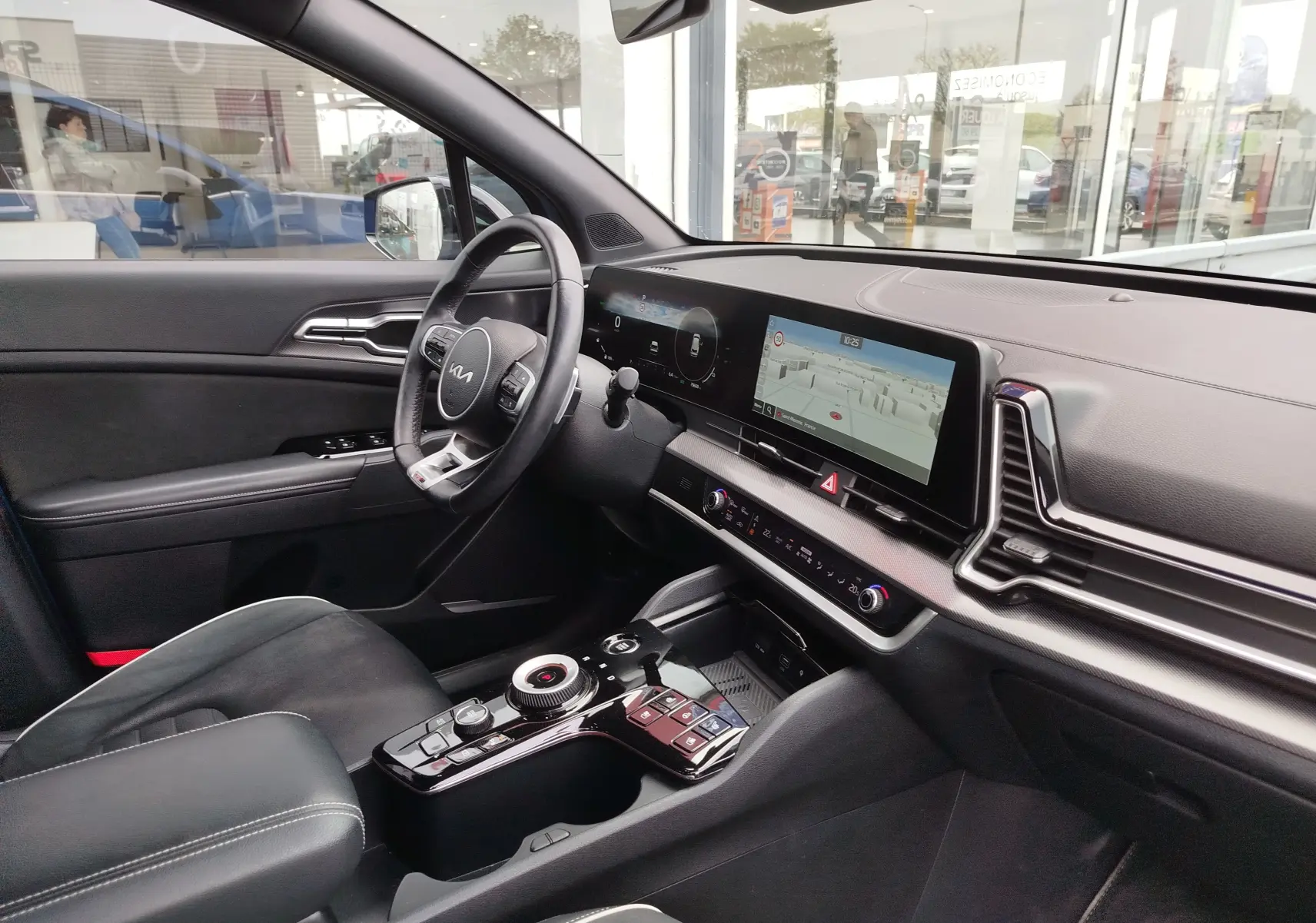 Vue intérieure côté conducteur du Kia Sportage 2022, tableau de bord numérique et console centrale moderne en noir.
