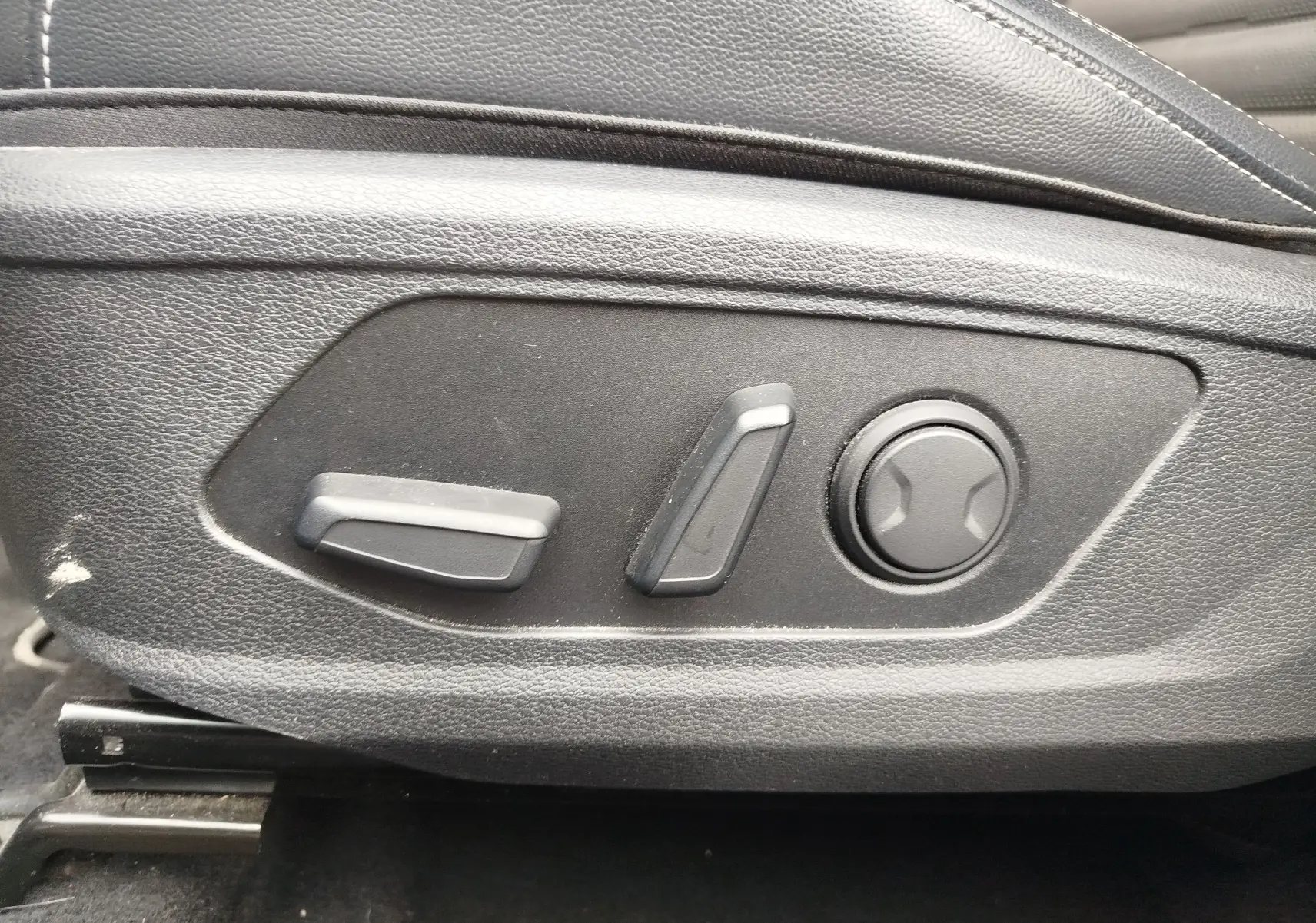 Détail des commandes de réglage électrique du siège conducteur en cuir noir dans un Kia Sportage 2022.