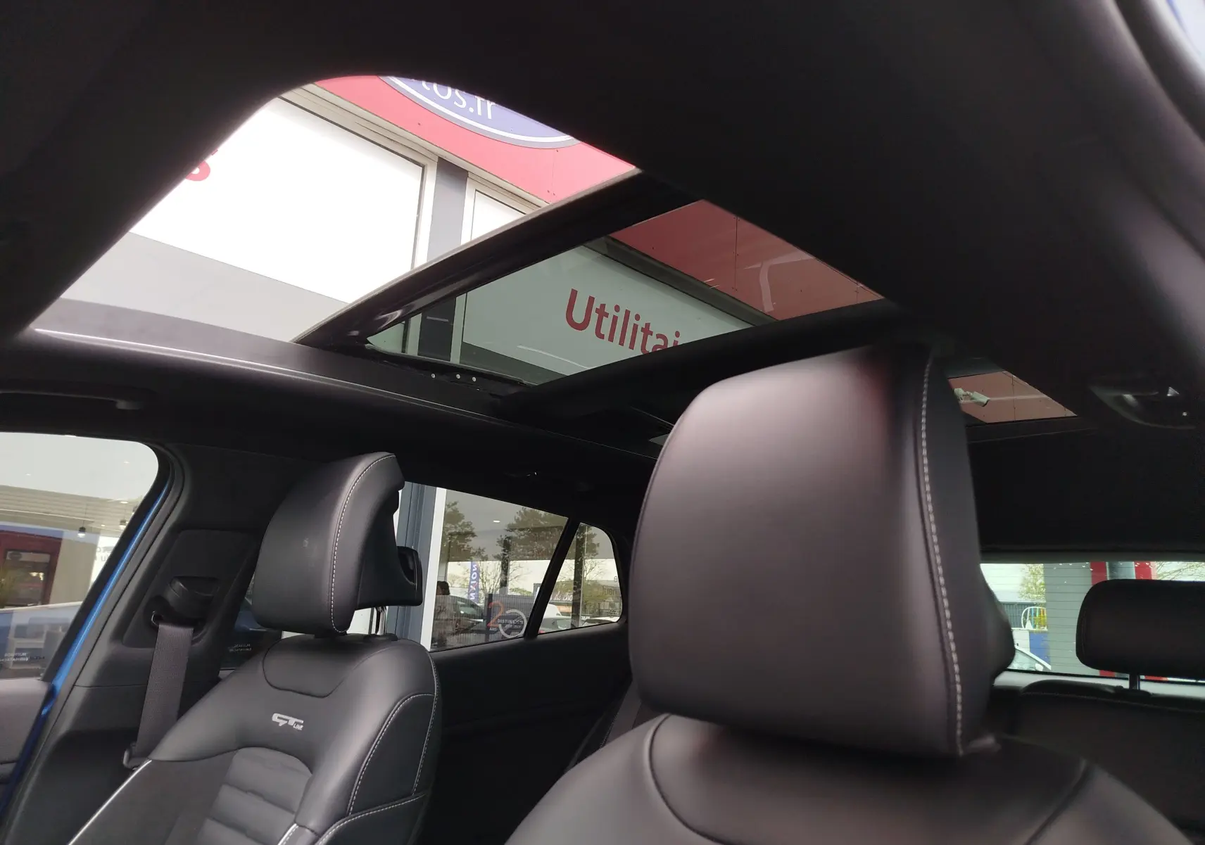 Vue intérieure du Kia Sportage bleu Fusion 2022, mettant en valeur les sièges en cuir noir GT-Line et le toit ouvrant panoramique.