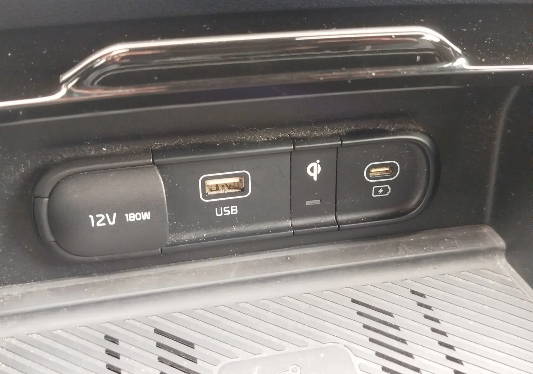 Gros plan sur les ports de charge USB, 12V et recharge sans fil du Kia Sportage 2022, intérieur noir.