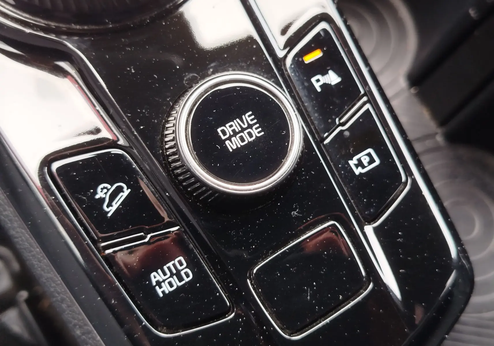 Gros plan sur la molette Drive Mode et les boutons de contrôle du frein à main et assistance stationnement dans le KIA Sportage 2022.
