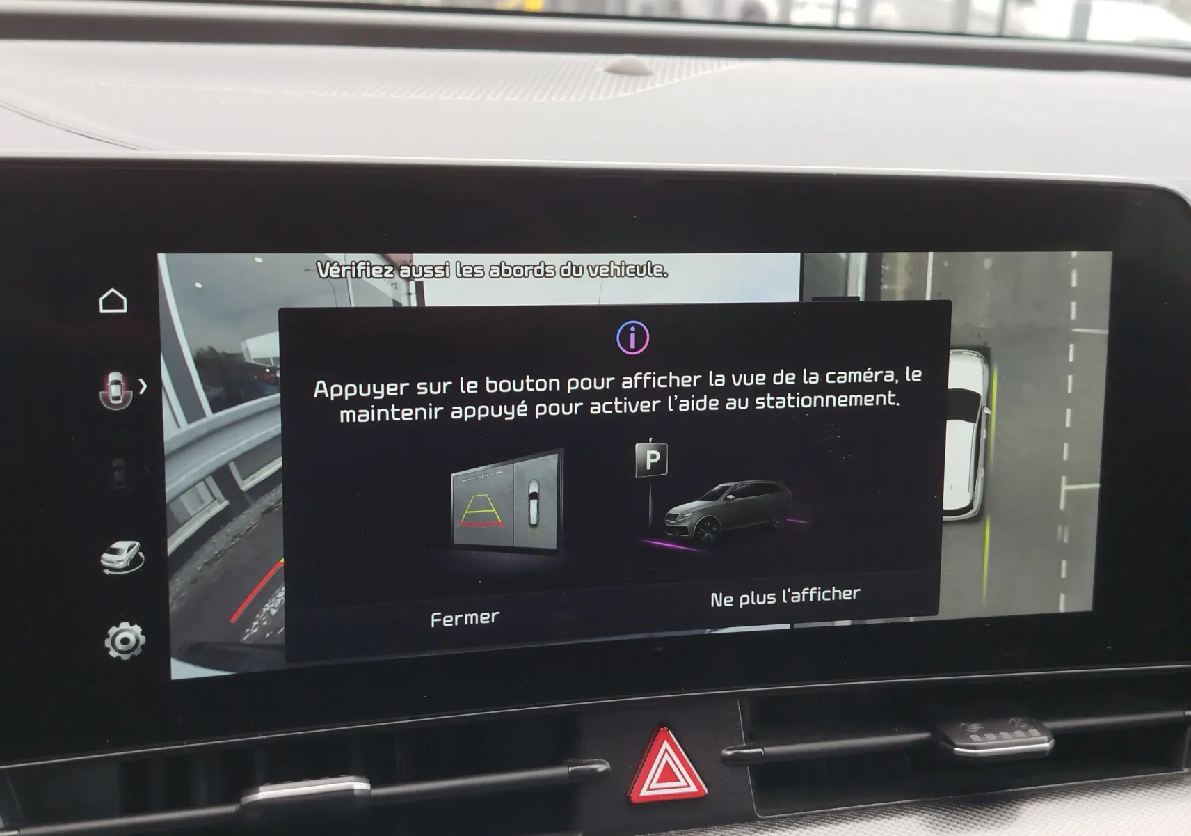 Écran tactile intérieur montrant l'aide au stationnement du Kia Sportage bleu, vue caméra 360° en affichage digital.