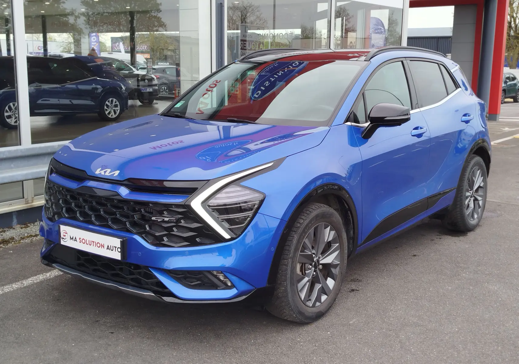 KIA Sportage bleu Fusion métallisé en 3/4 avant droit, avec calandre noire et signature lumineuse en forme de flèche.