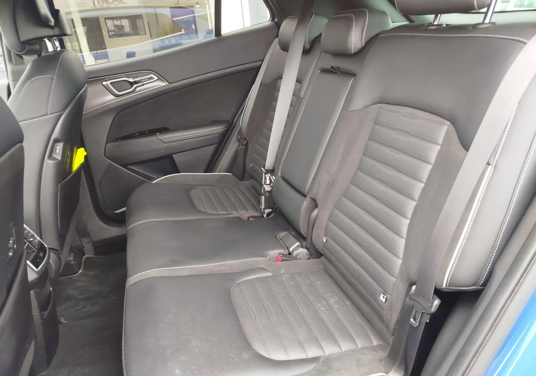 Vue intérieure côté droit des sièges arrière en cuir noir avec surpiqûres blanches du Kia Sportage bleu métallisé 2022.