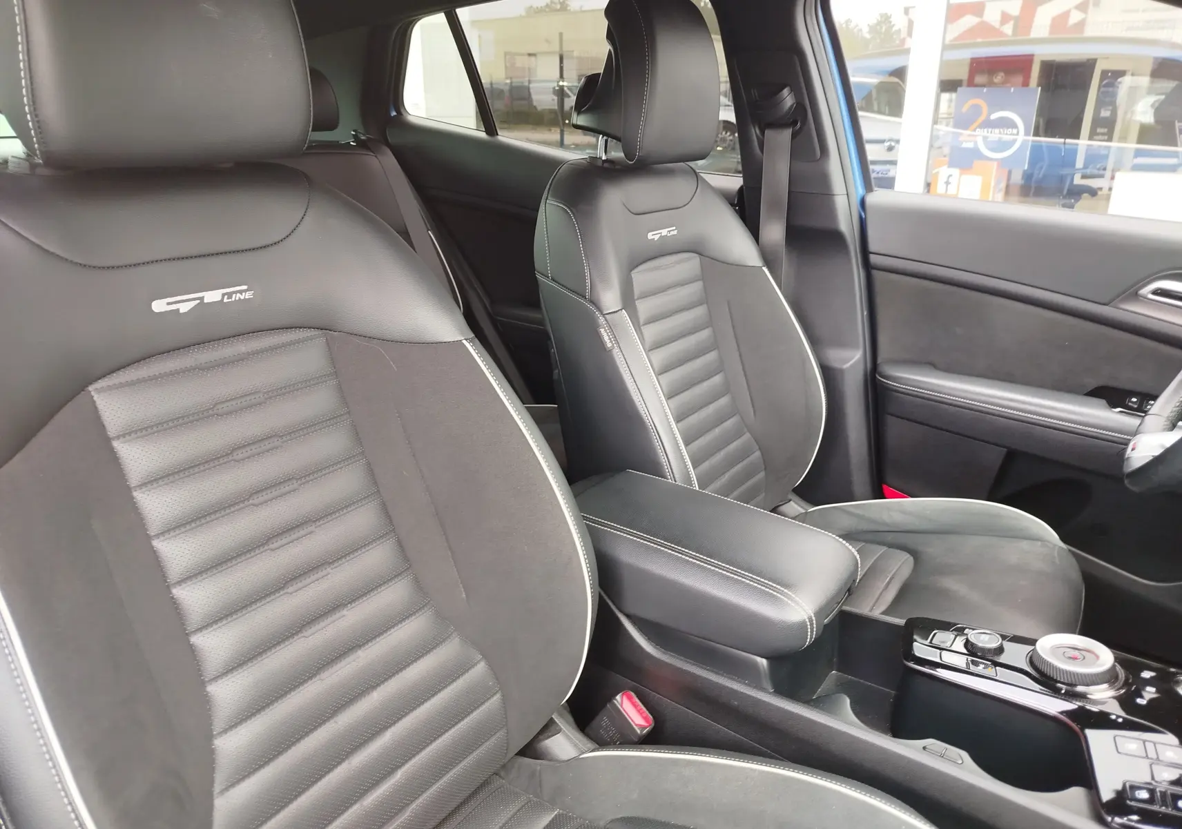 Vue intérieure du Kia Sportage 2022, sièges avant GT-Line en cuir noir avec surpiqûres blanches et logo brodé.