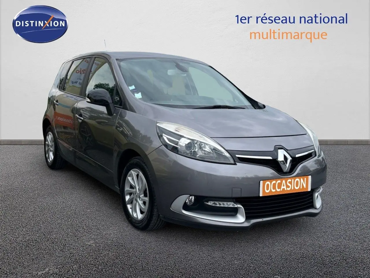 Renault Scénic III gris en 3/4 avant droit avec plaque "OCCASION" sur fond neutre blanc.
