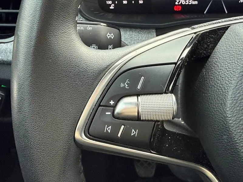 Gros plan sur les commandes gauche du volant du Skoda Kamiq 2024, avec molette métallique et boutons multifonctions.