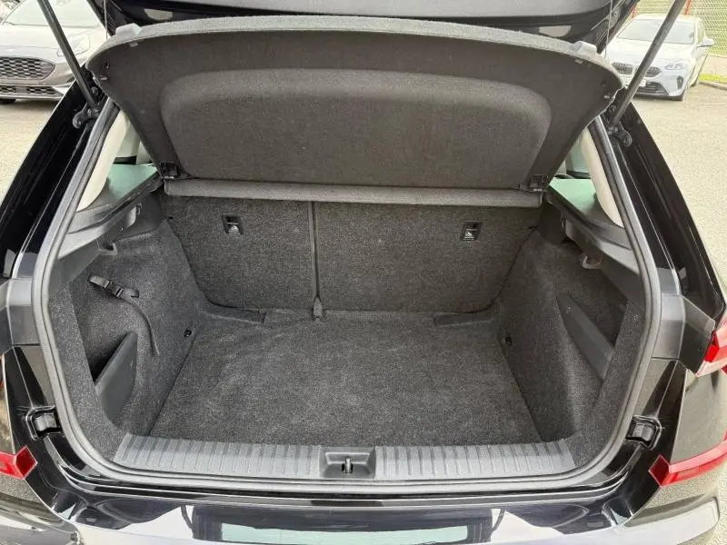 Coffre ouvert vu de l'arrière d'un Skoda Kamiq 2024 noir Magic nacré, montrant un espace de chargement vide et propre.
