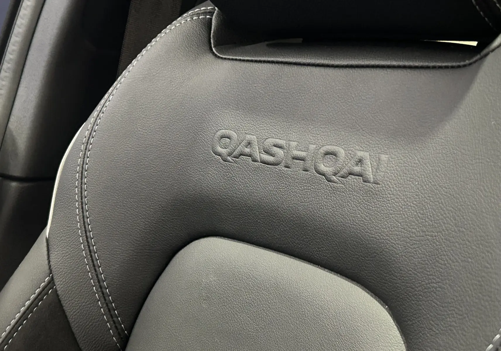 Gros plan sur l'appui-tête en cuir noir embossé du logo QASHQAI à l'intérieur du Nissan Qashqai 2025.