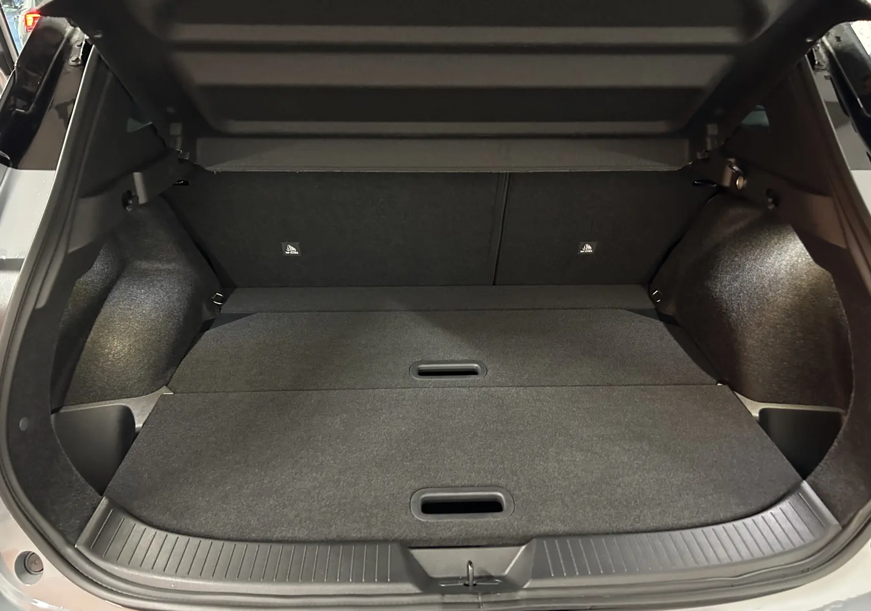 Coffre ouvert du Nissan Qashqai 2025 gris céramique, vue intérieure arrière montrant l'espace de chargement plat.