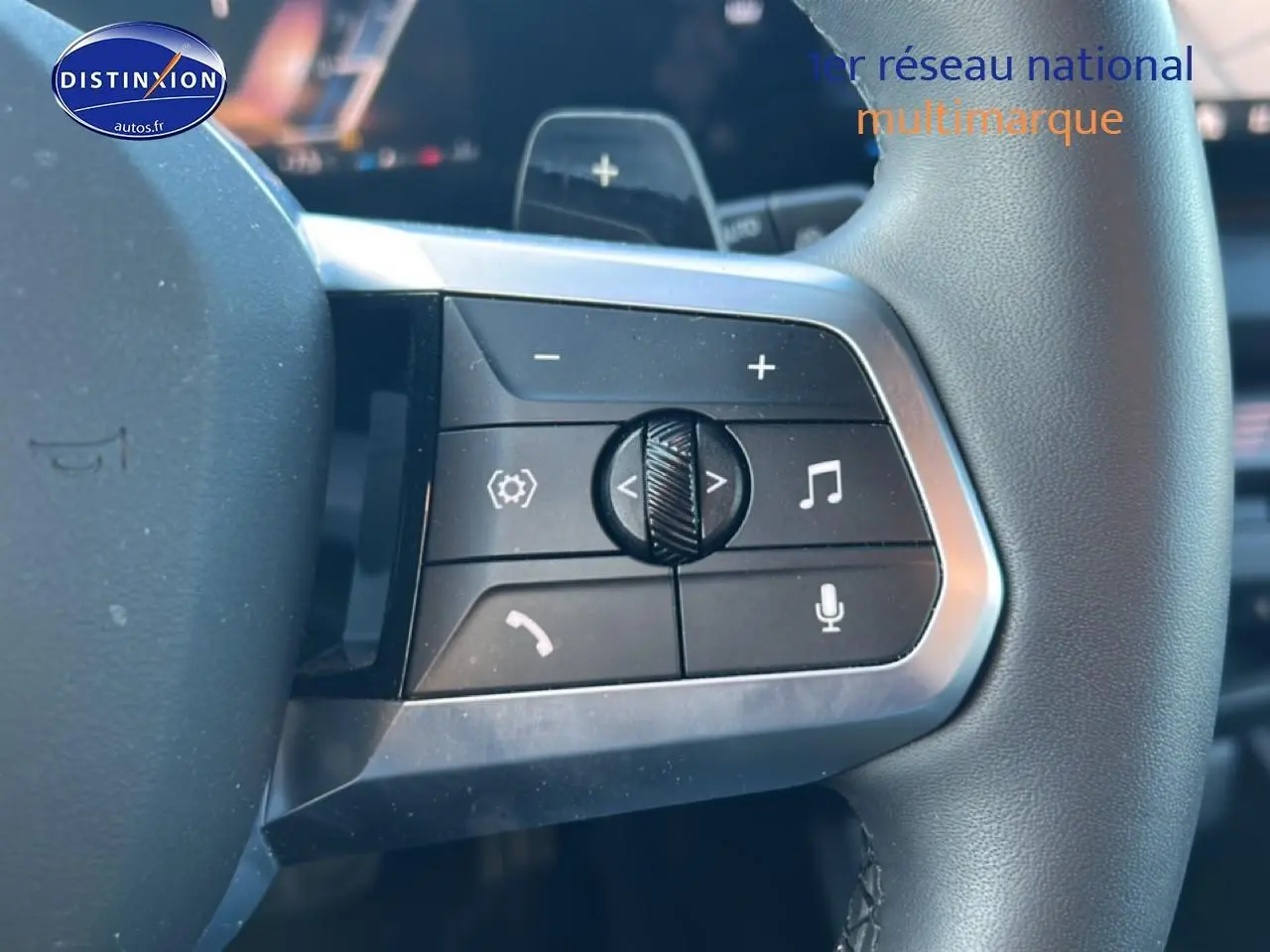 Gros plan sur les commandes multifonctions au volant d'une BMW Série 1 blanche, avec boutons de volume et appels.