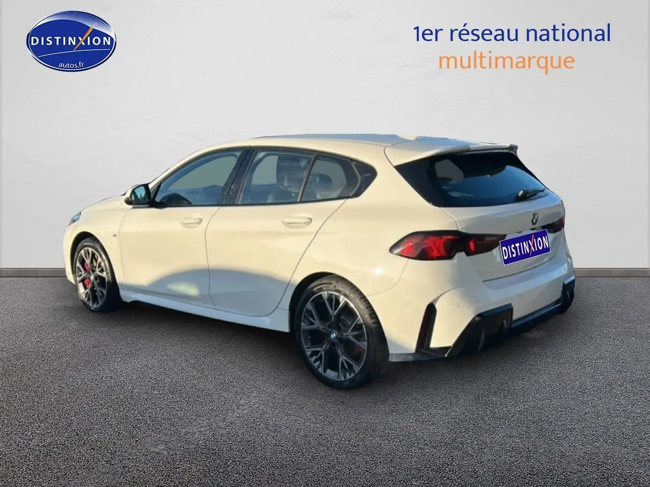 BMW Série 1 blanche alpin vue 3/4 arrière droit, jantes 18 pouces bicolores et feux arrière LED distinctifs.