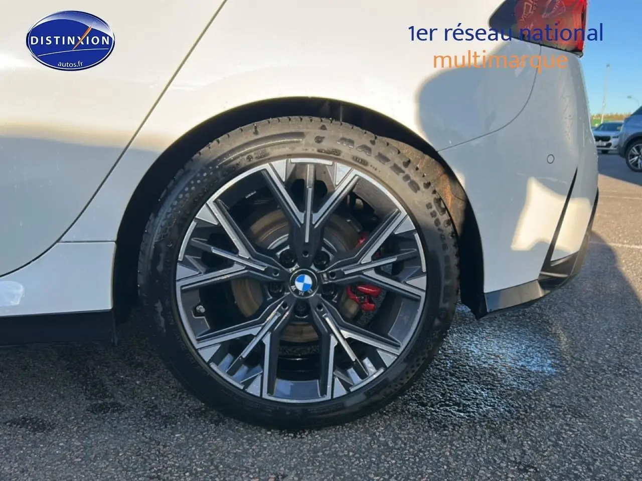 Gros plan sur la roue arrière droite de la BMW Série 1 blanche avec jante 18 pouces bicolore style Y et étrier de frein rouge.