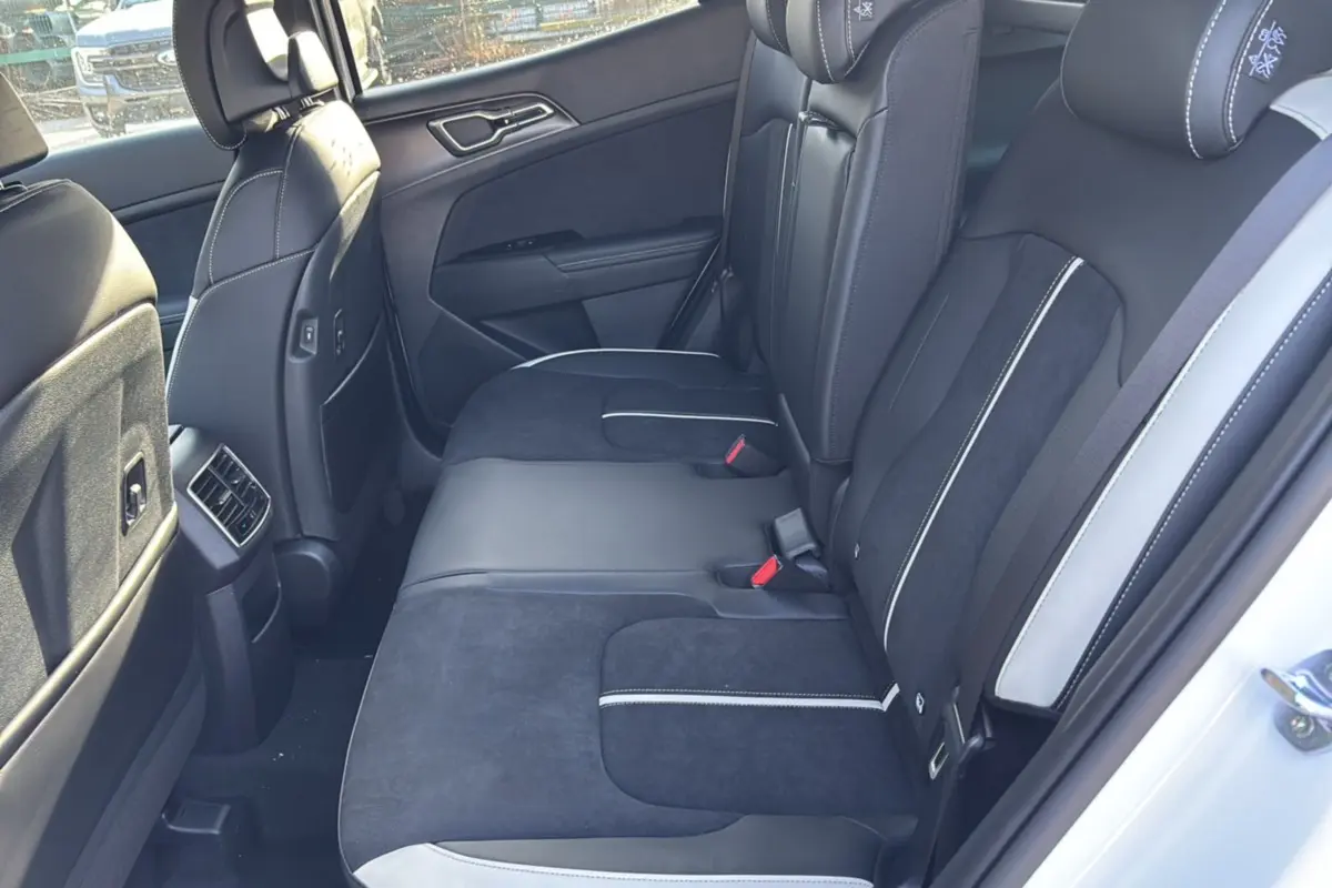 Vue côté gauche de la banquette arrière en cuir noir et alcantara avec surpiqûres blanches du Kia Sportage blanc nacré 2026.