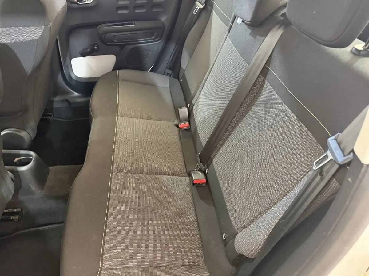 Vue intérieure sur la banquette arrière côté droit de la Citroën C3 blanche avec sièges tissu gris et ceintures noires.