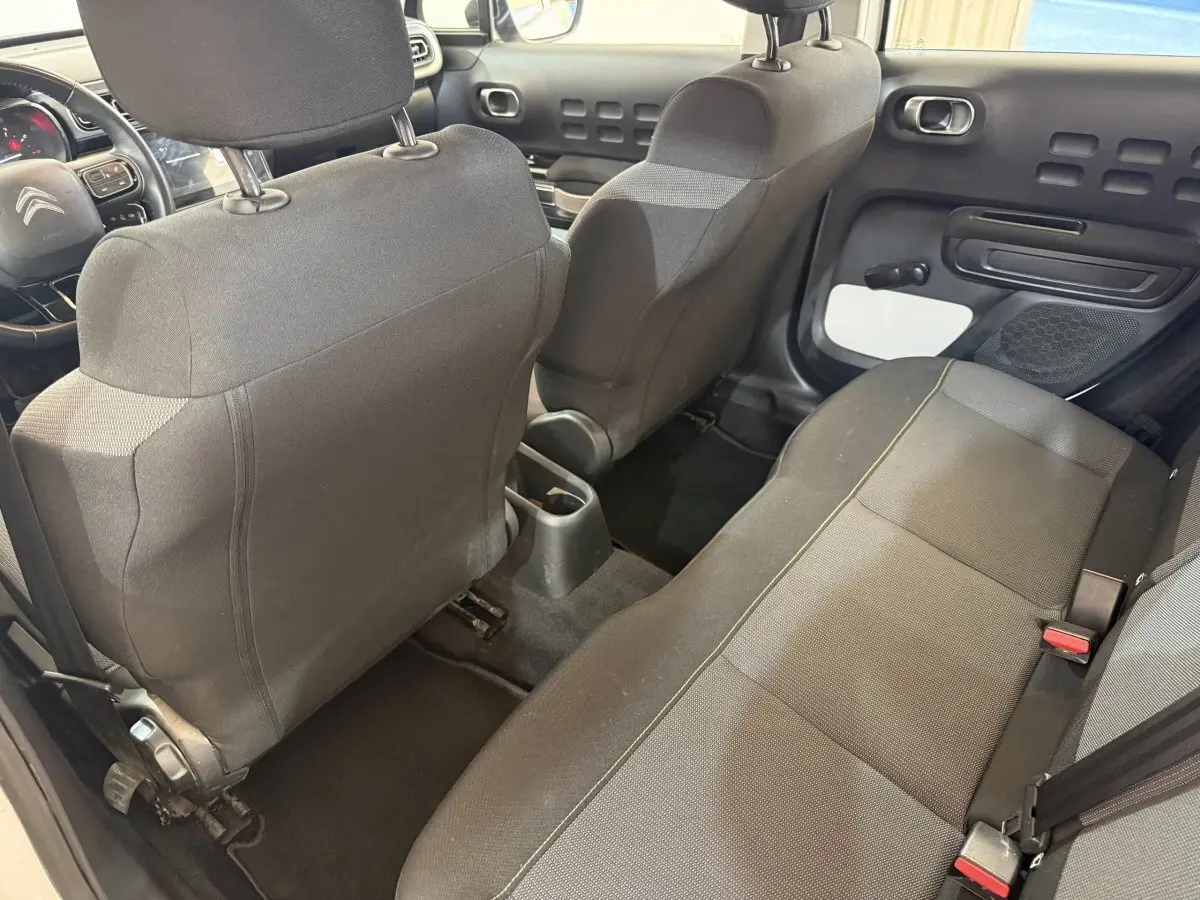 Vue intérieure arrière côté droit de la Citroën C3 blanche 2021, montrant les sièges tissu gris et la porte avec inserts blancs.