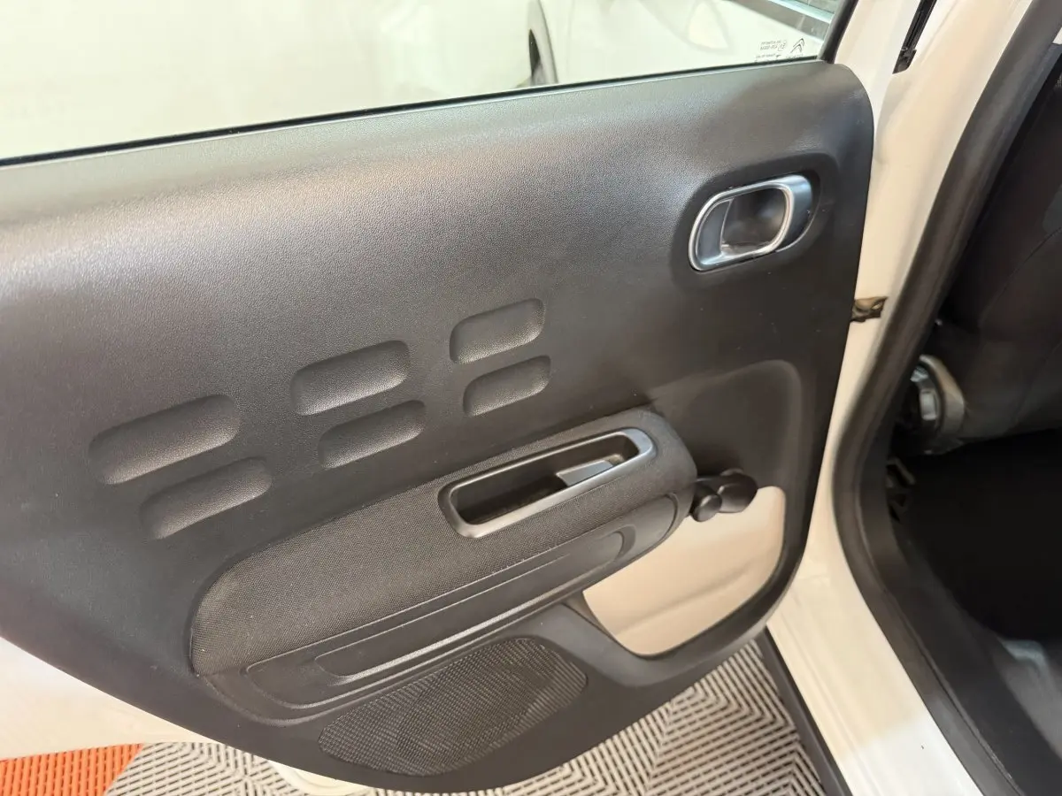 Vue intérieure de la porte arrière droite noire avec poignée et manivelle sur Citroën C3 blanc 2021.
