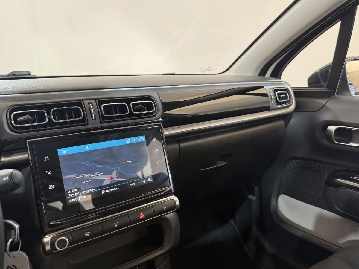 Vue intérieure côté passager du tableau de bord noir brillant et écran tactile 7 pouces de la Citroën C3 blanche 2021.