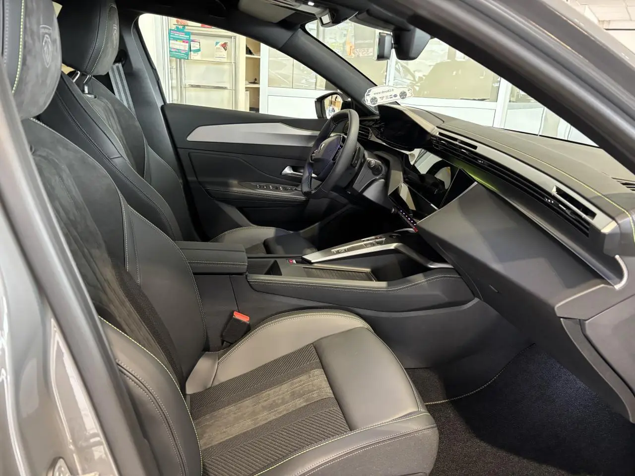 Vue intérieure côté conducteur de la Peugeot 308 gris selenium, avec sièges Alcantara noirs et surpiqûres vert Adamite.