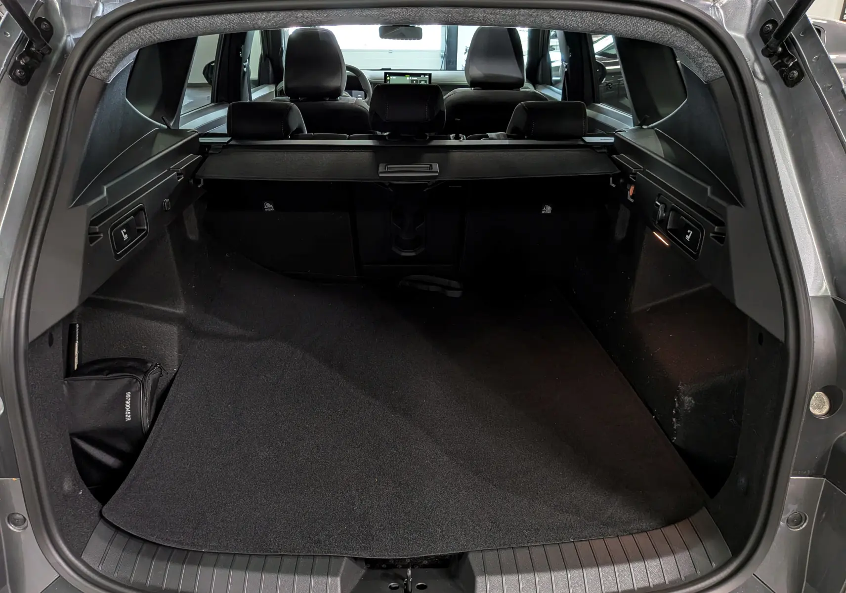 Coffre ouvert vu de l'arrière d'un Dacia Bigster Hybrid-G 150 4x4 Extrême gris, montrant l'espace de chargement et la tablette arrière.
