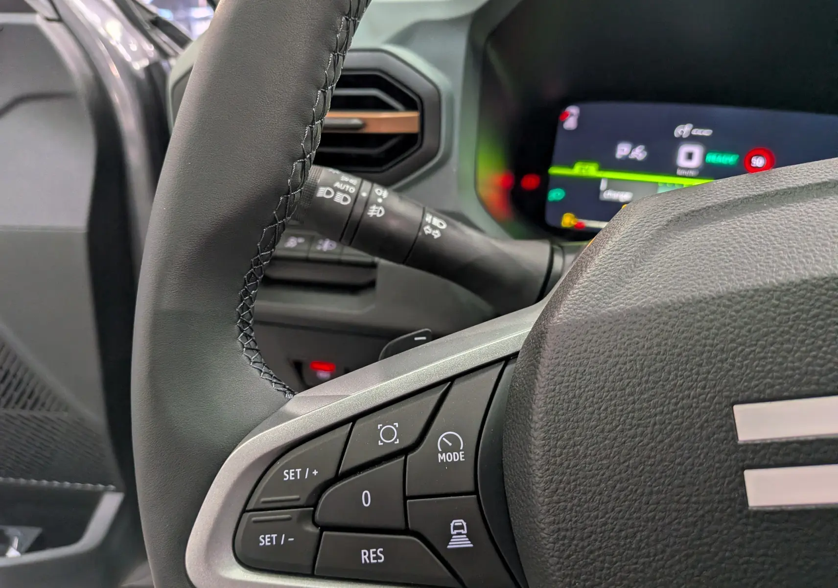 Gros plan sur le volant noir et les commandes multifonctions du tableau de bord du Dacia Bigster Hybrid-G 150 4x4.