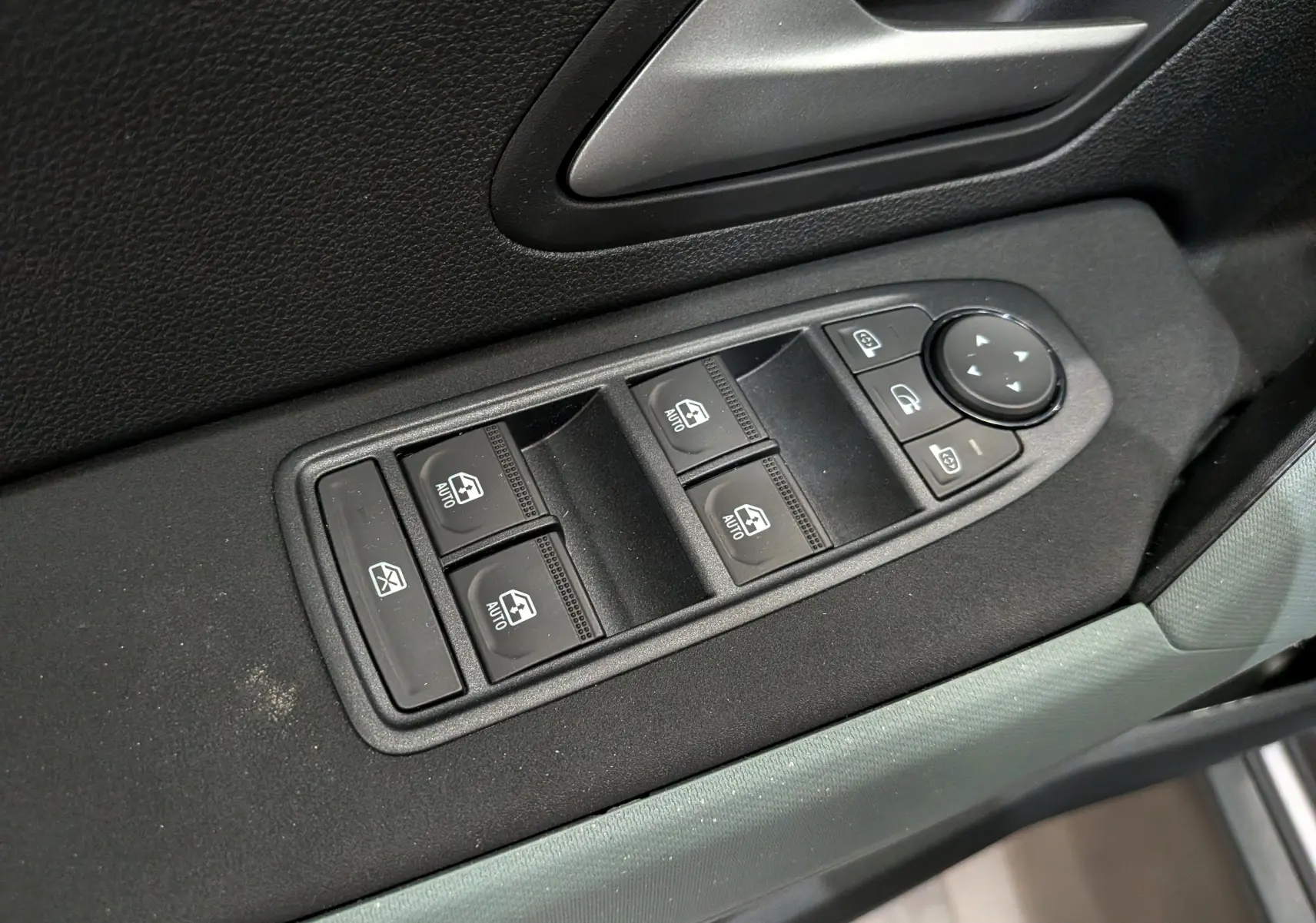 Gros plan sur les commandes des vitres électriques et des rétroviseurs côté conducteur du Dacia Bigster Hybrid-G 150 4x4 Extrême.