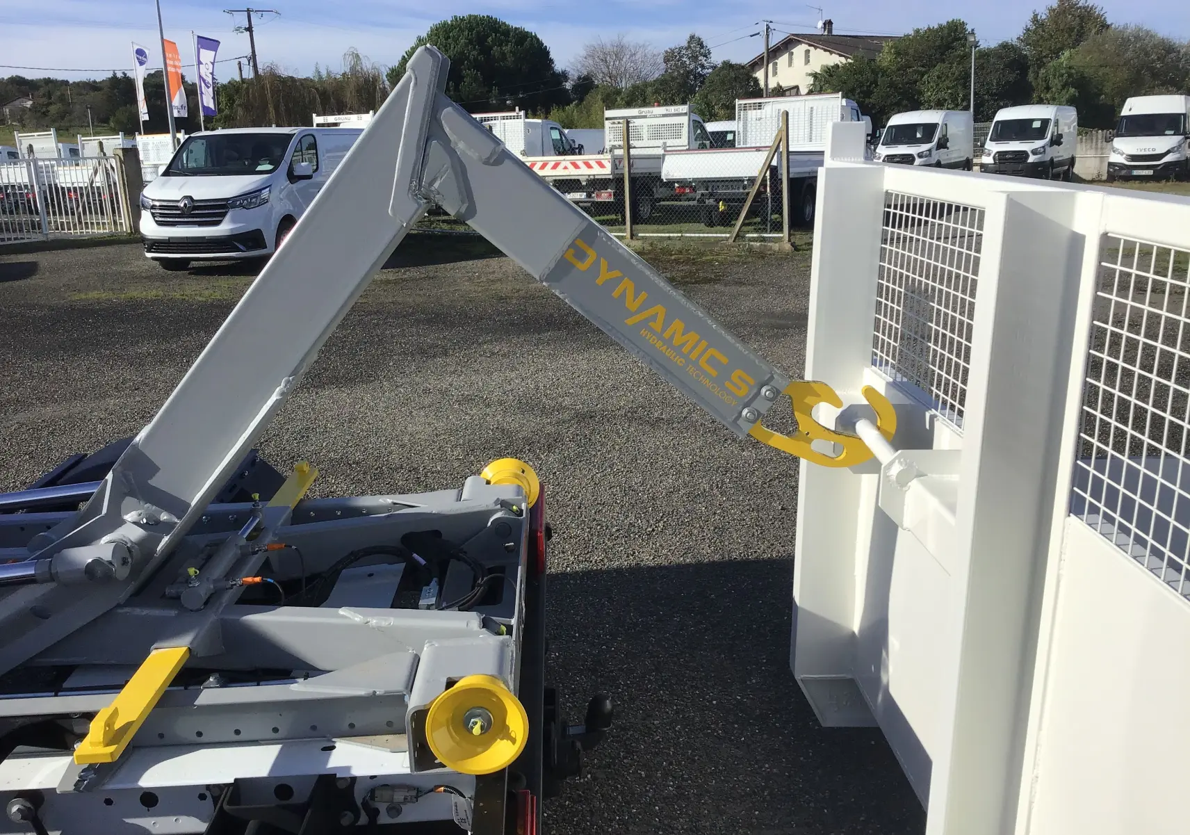 Gros plan sur le bras polybenne gris et jaune du Ford Transit Chassis Cabine blanc, vue arrière droite.