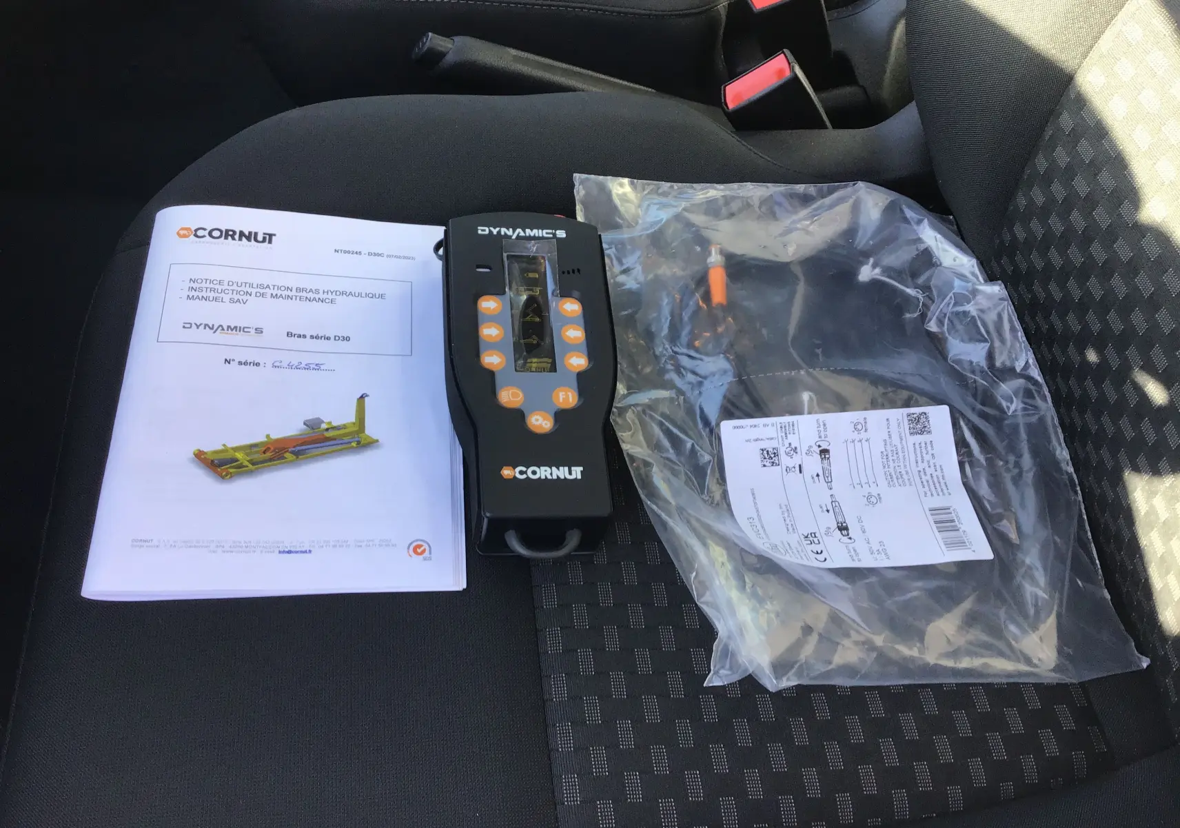 Vue intérieure du siège passager du Ford Transit Chassis Cabine blanc avec notice, télécommande et câble du bras Polybenne Cornut.