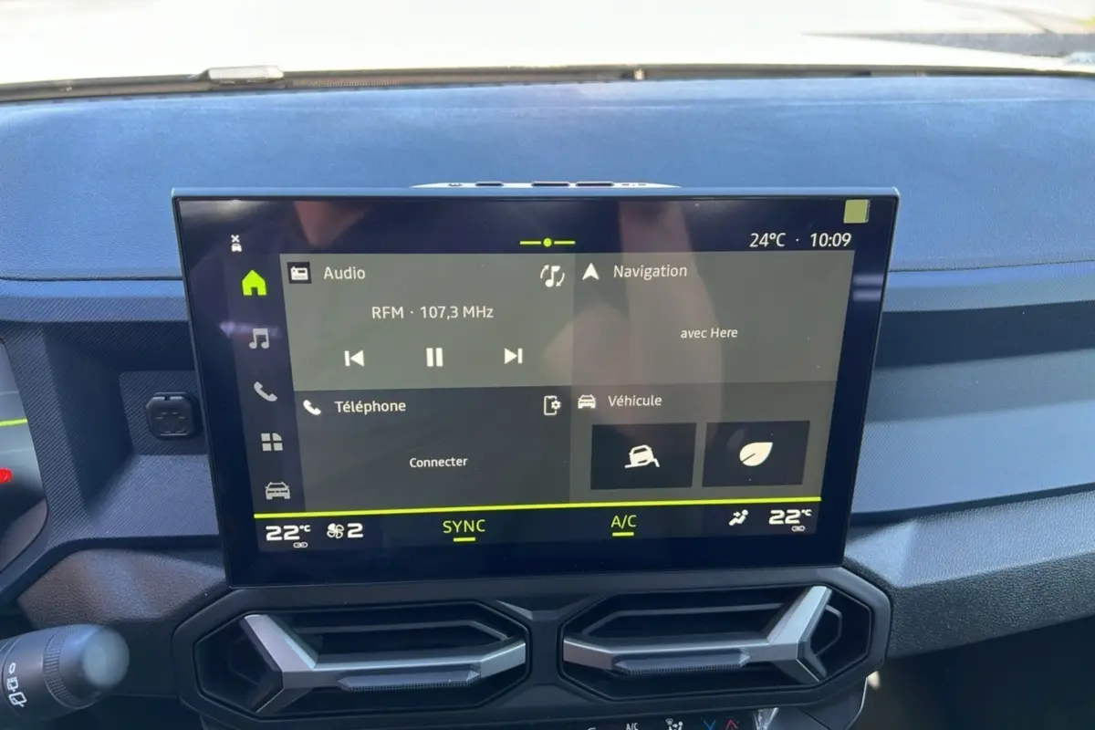 Écran tactile central du tableau de bord du Dacia Bigster 2025, affichant radio, navigation et climatisation.