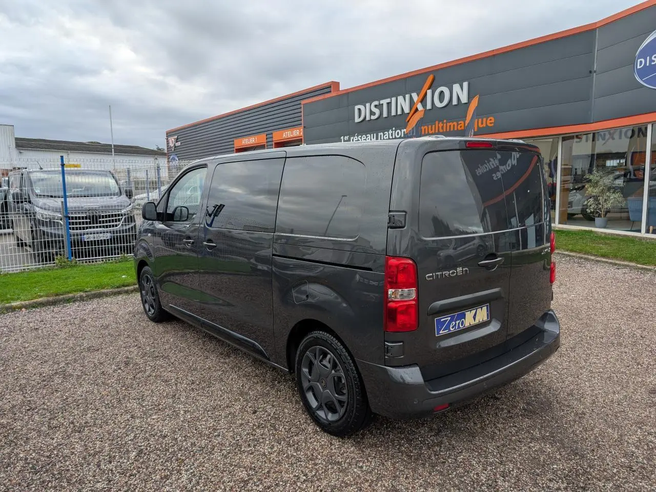 Vue 3/4 arrière droite d'un Citroën Jumpy gris avec vitres latérales surteintées et boucliers couleur carrosserie.
