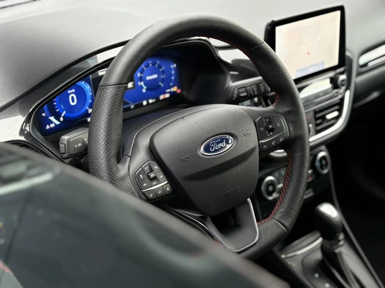 Vue rapprochée du volant ST-Line noir avec surpiqûres rouges et tableau de bord numérique bleu du Ford Puma 2023.